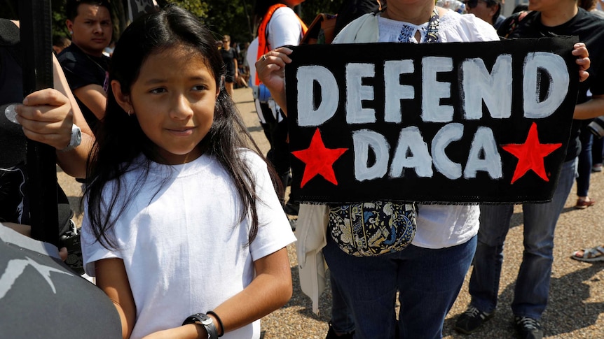 Demonstrators hold "Defend DACA" signs during a protest in front of the White House.