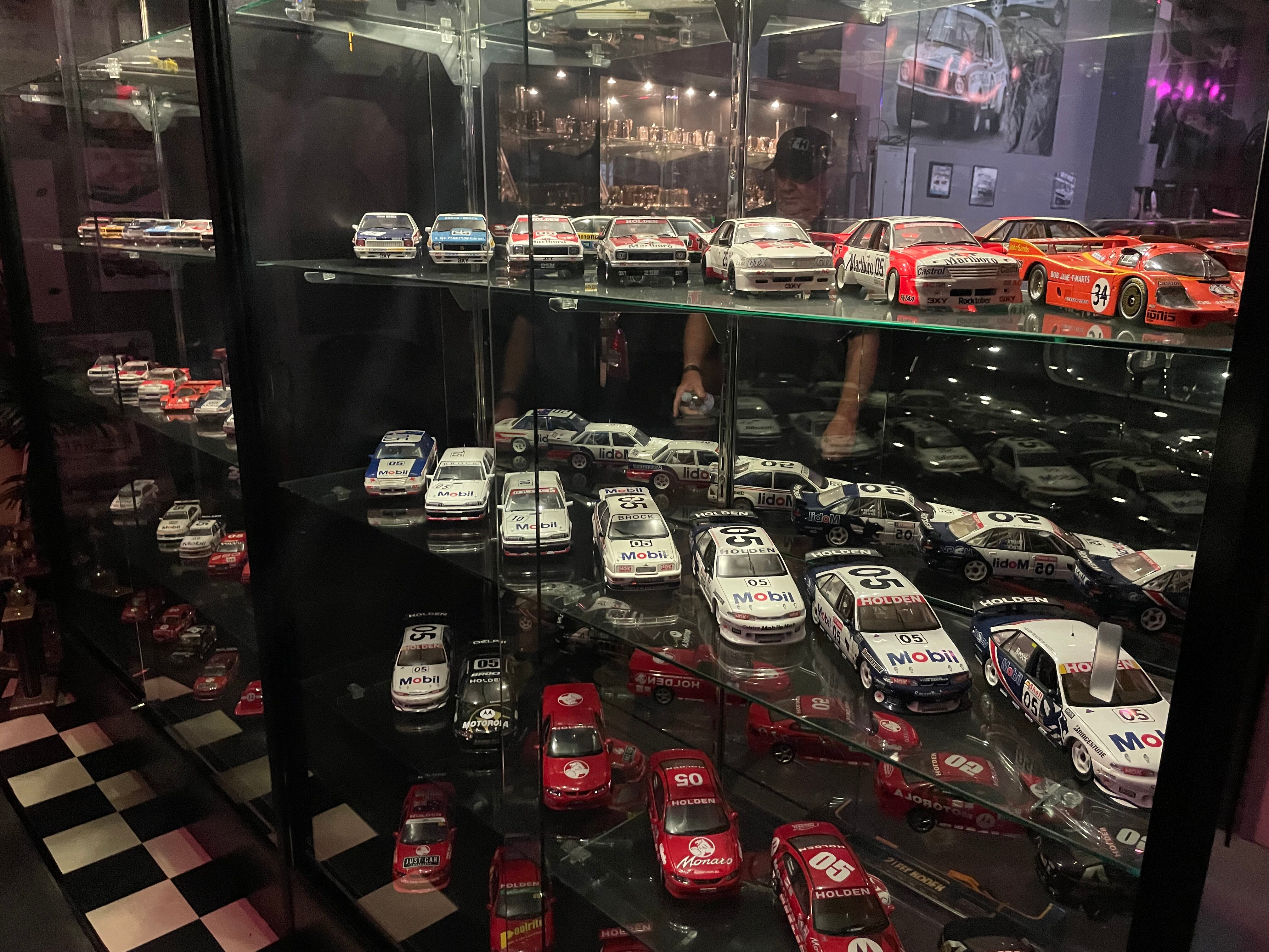 A collection of model cars of all the racing cars that Peter Brock has driven sits in a cupboard.