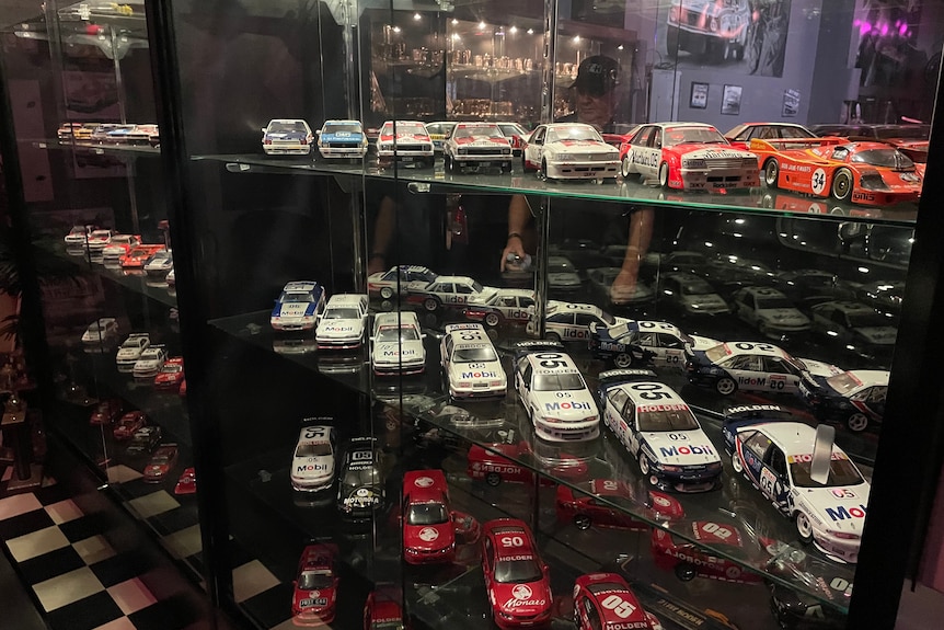 A collection of model cars of all the racing cars that Peter Brock has driven sits in a cupboard.