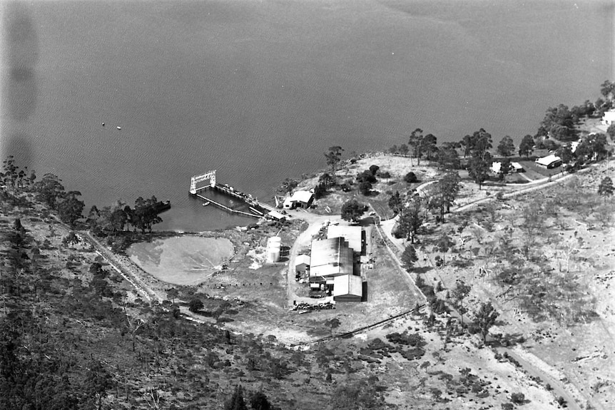 Black and white photo of a small factory on the coast.