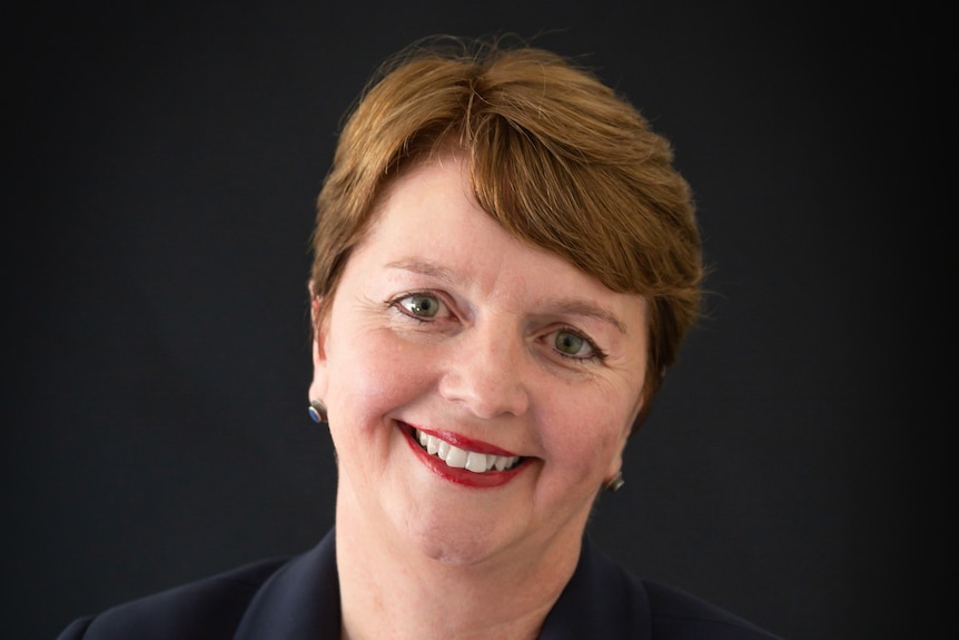 Woman smiles at camera with black background