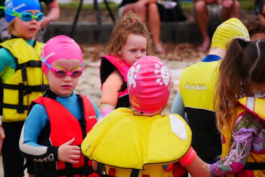 Children in lifejackets and swimming costumes
