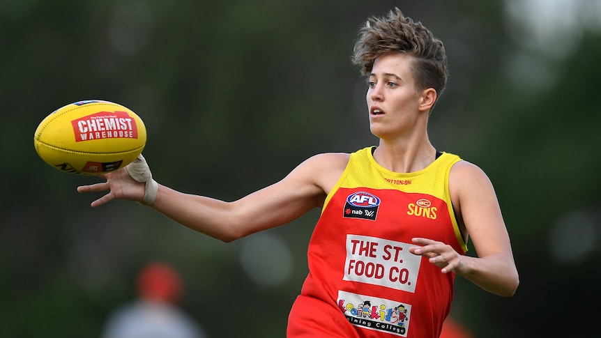 The Suns' Tori Groves-Little reaches for the ball mid-air with their right hand. They are wearing Gold Coast training gear