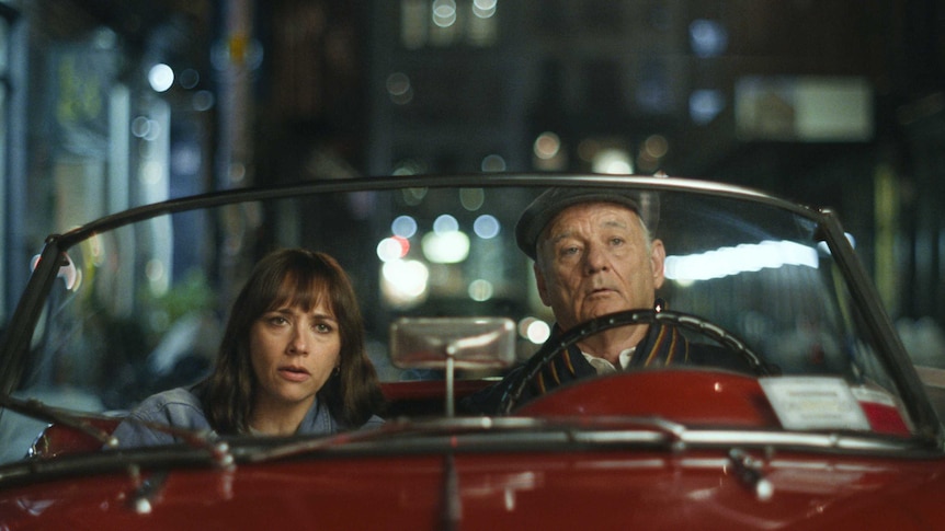 Rashida Jones and Bill Murray sit in an old red convertible in the film On the Rocks