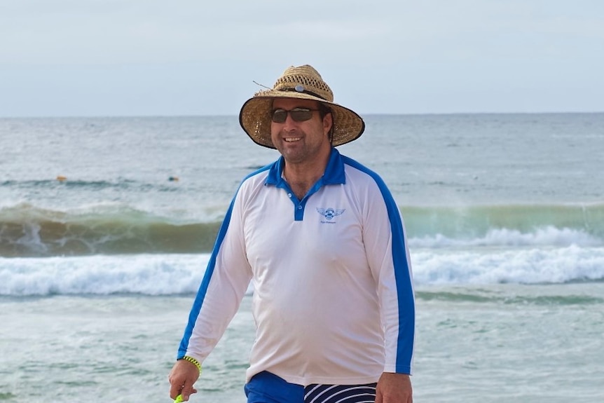 man with straw hat at beach smiling 