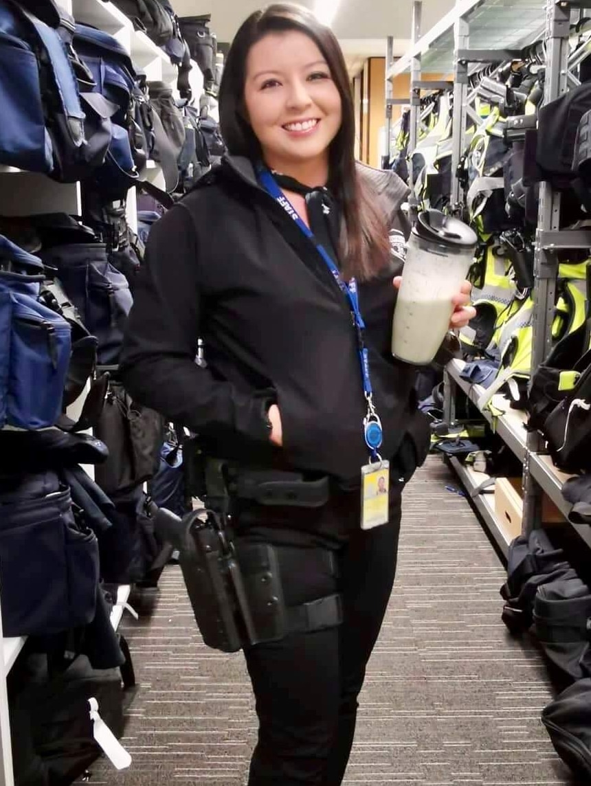 A woman stands in a changing room full of law enforcement gears.