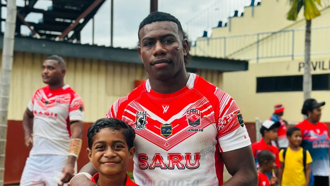 Man in rugby jersey with arm draped over shoulder of young boy
