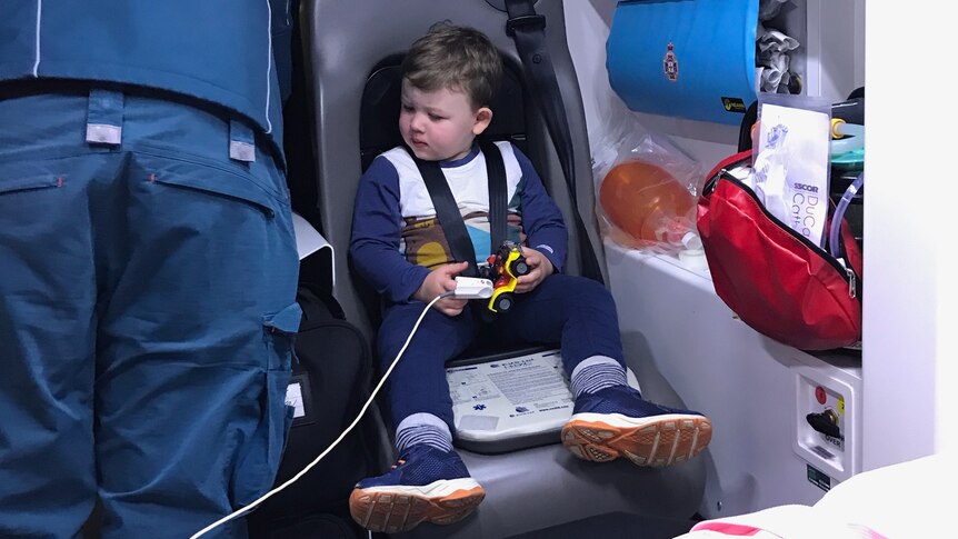 A little boy sits in a chair in an ambulance