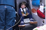 A little boy sits in a chair in an ambulance