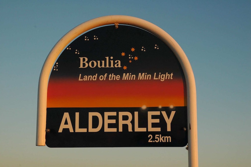 A sign which reads Boulia: Land of the Min Min Light, then a station name, Alderley Station