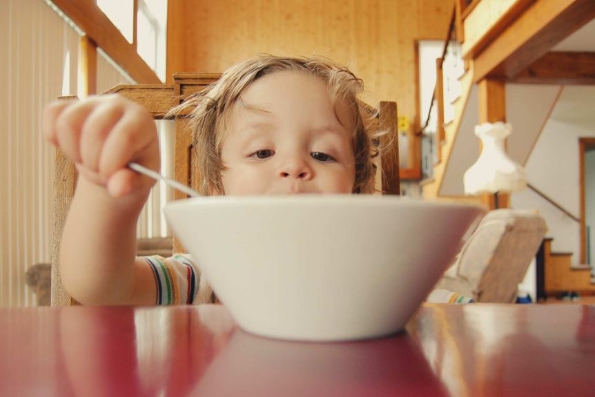 Small child eating from a bowl with a spoon