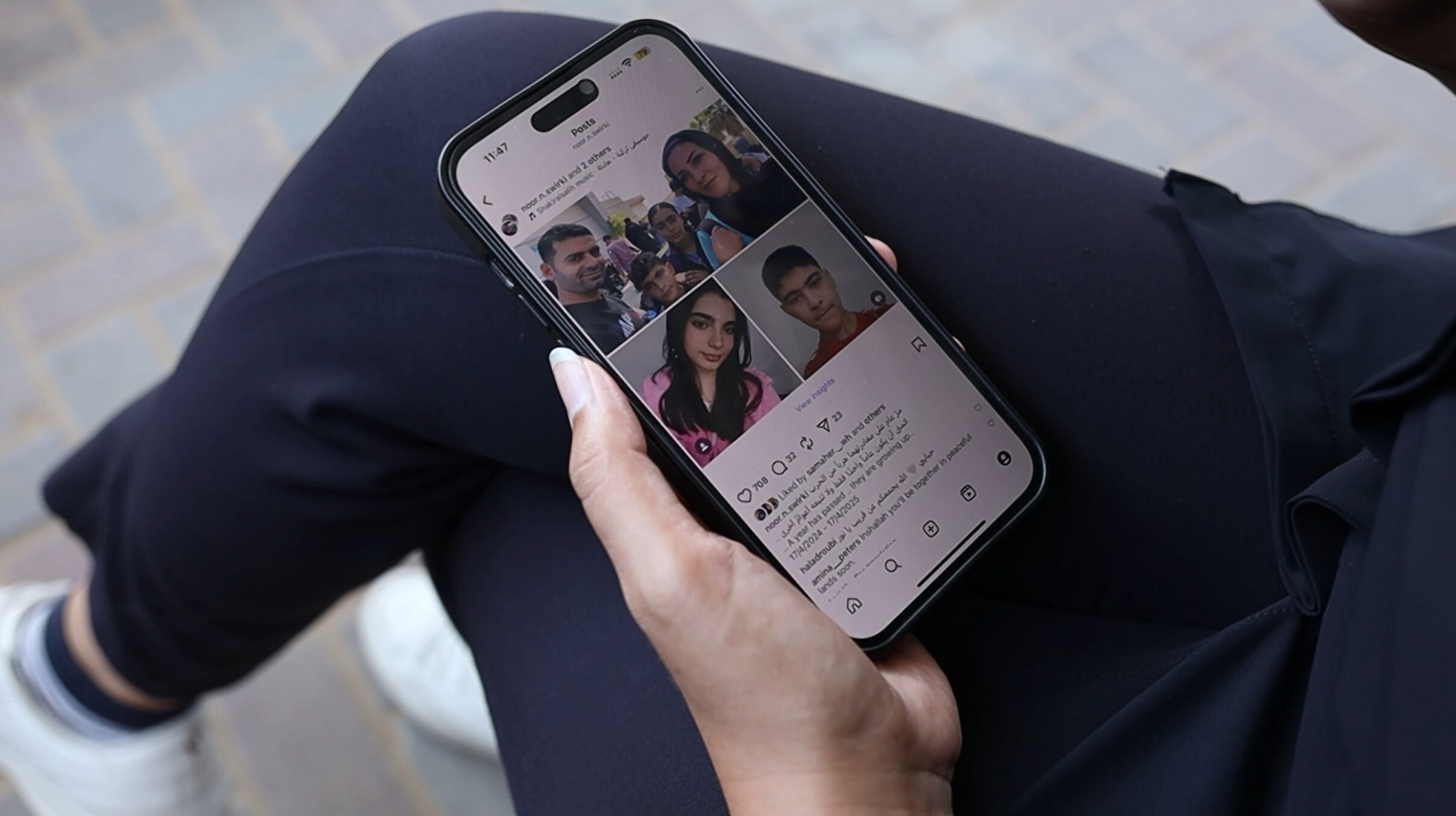 A person's hand holding a phone with photos of a family 