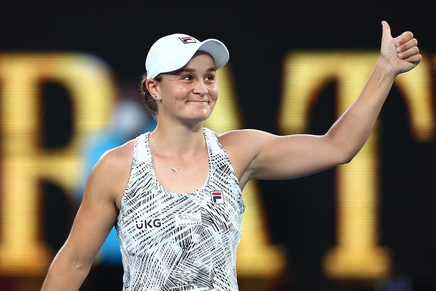 An Australian female tennis player gives the thumbs up to the crowd with her left hand.