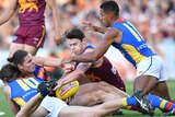 Brisbane Lions and Gold Coast Suns AFL players contest the ball on the ground.