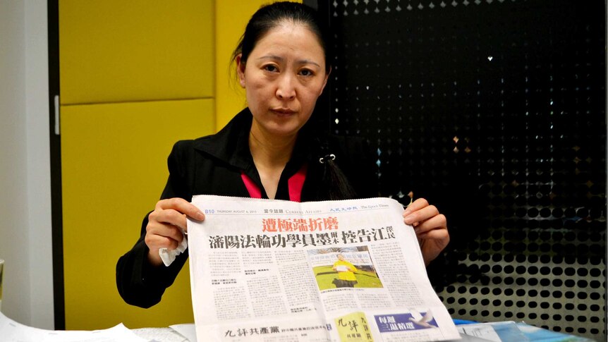 Woman holding a newspaper behind a table full of paperwork
