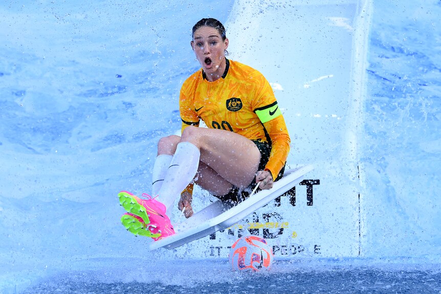 AFLW player Tayla Harris wears a Matildas jersey as she slides into ice water at the Big Freeze at the G MND fundraiser.