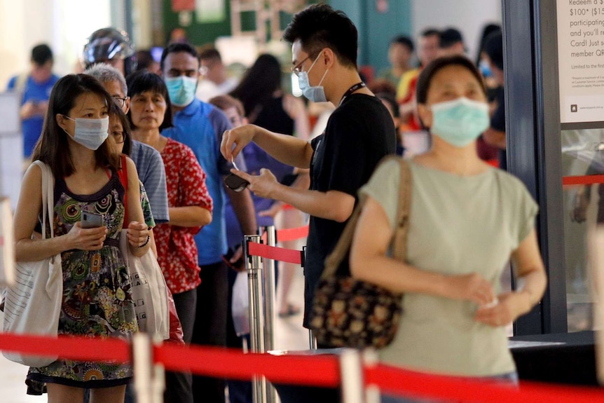 People in malls queue at a temperature checking point.