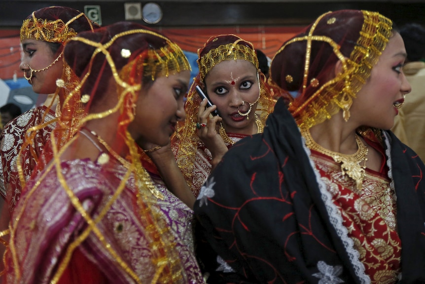 Three Indian brides speak on their phones. 