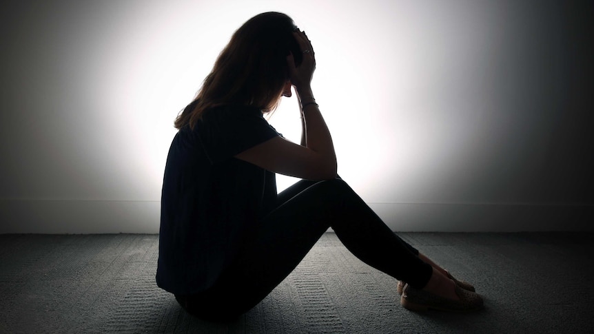 Stock image of a anonymous woman holding her head in her hands.