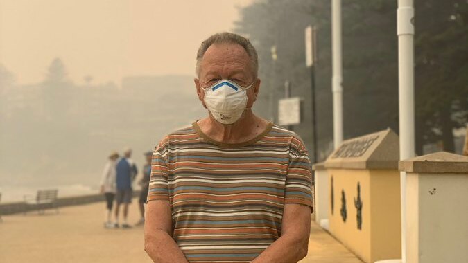 Man stands at smoky beach with face mask