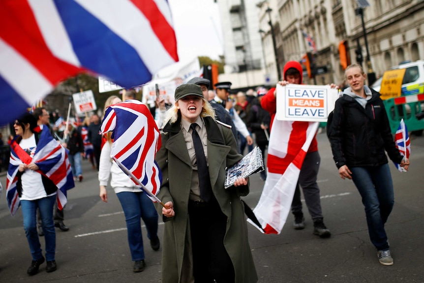 A woman shouting during a protest clutching a union jack flag