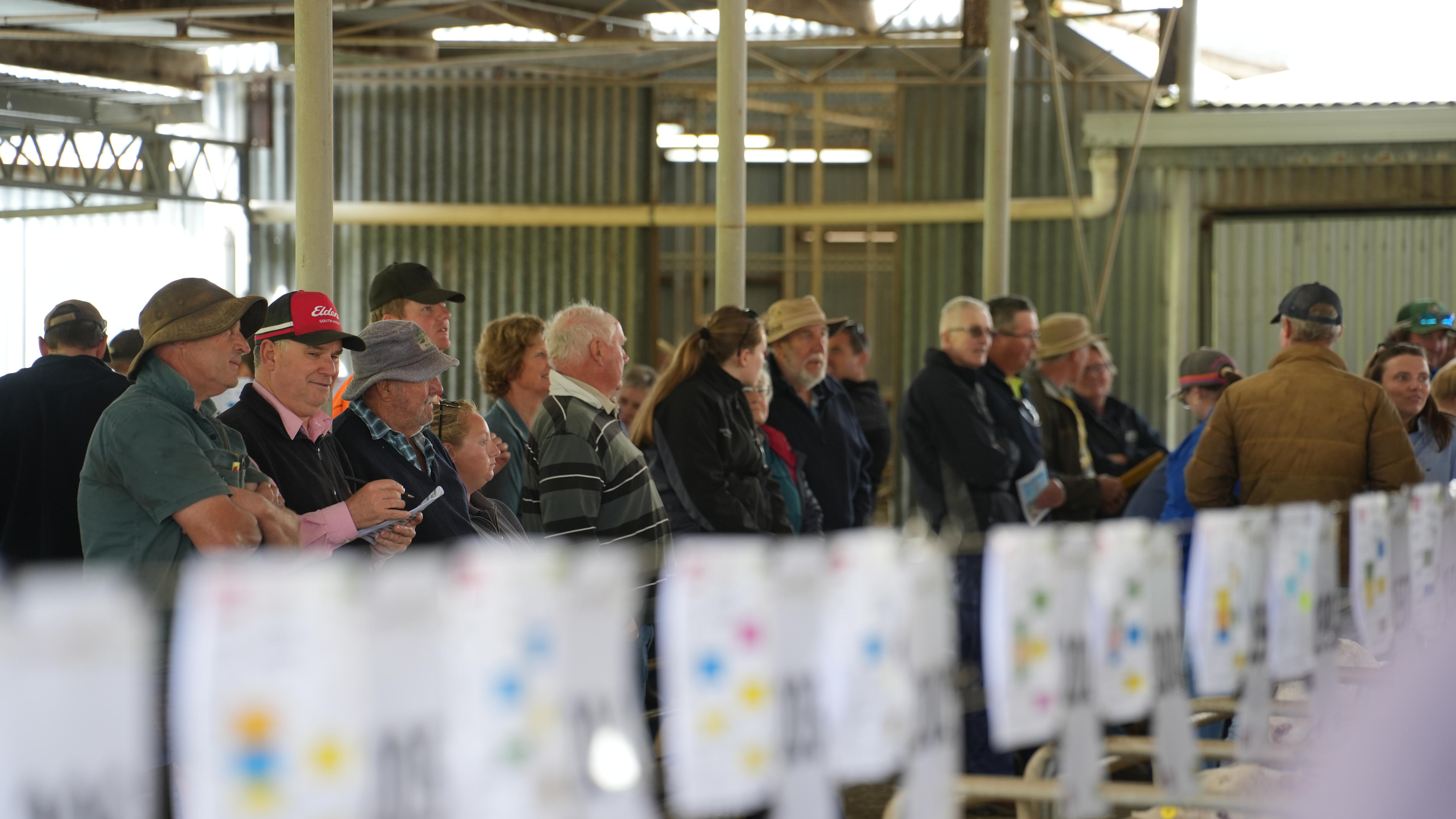 a group of men speaking in a shed