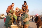 Kurdish security forces help an elderly man from the minority Yazidi sect
