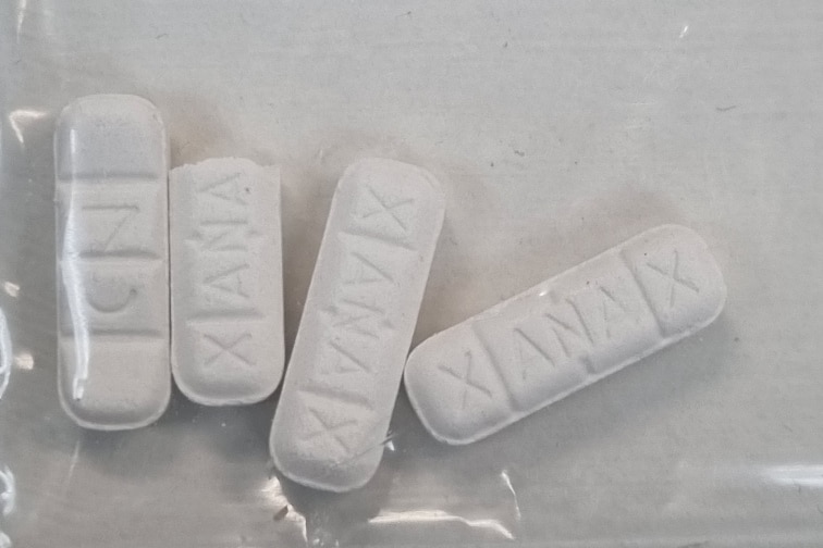 White tablets stamped with the word 'xanax' in a clear plastic bag
