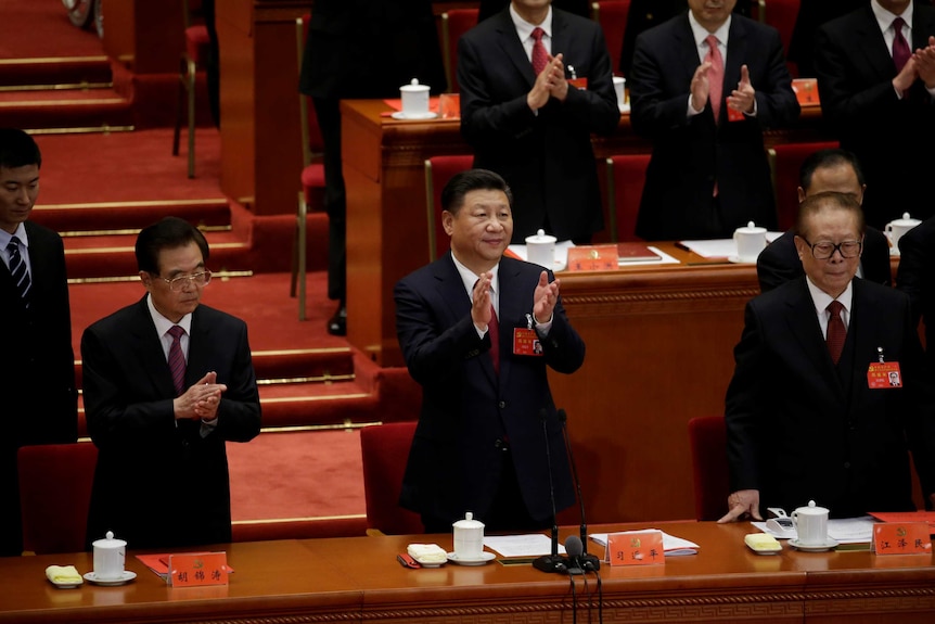 Chinese President Xi Jinping is standing up and clapping at the national congress.