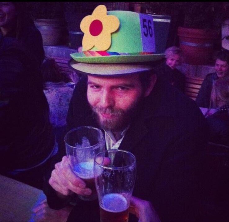 A man holding a beer wearing a flower hat