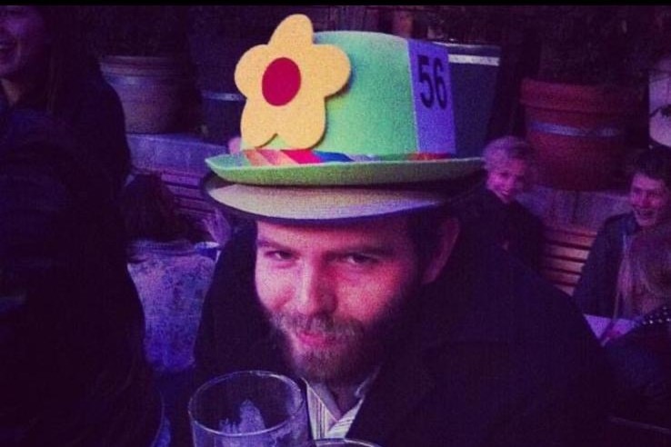 A man holding a beer wearing a flower hat