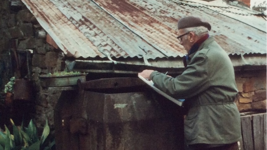 Man standing in front of shed painting