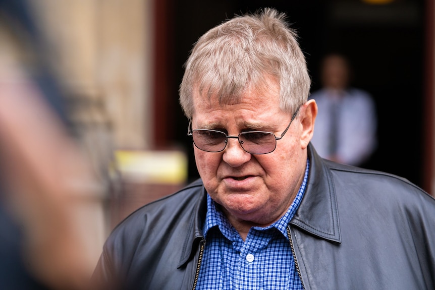 Une photo en gros plan d'un homme portant des lunettes et une veste en cuir noir.