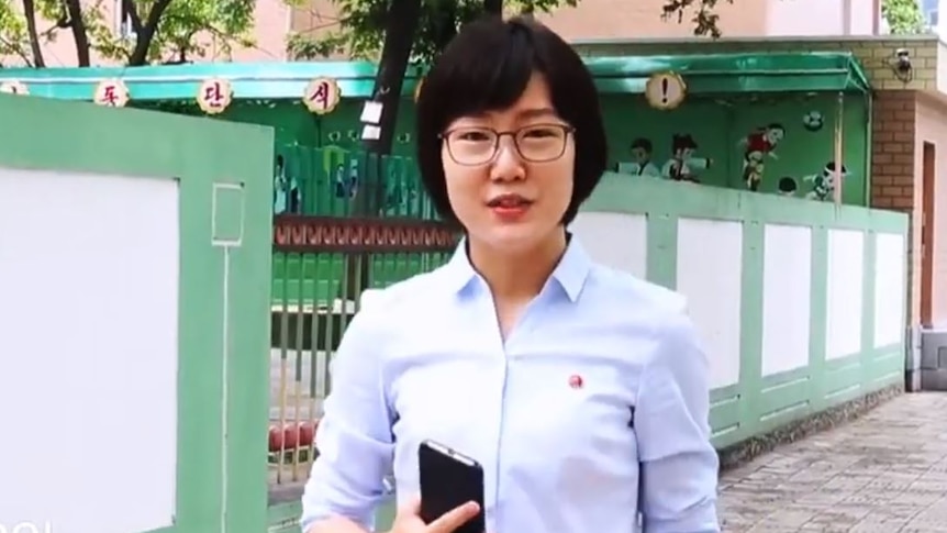 A young woman holds a phone. 