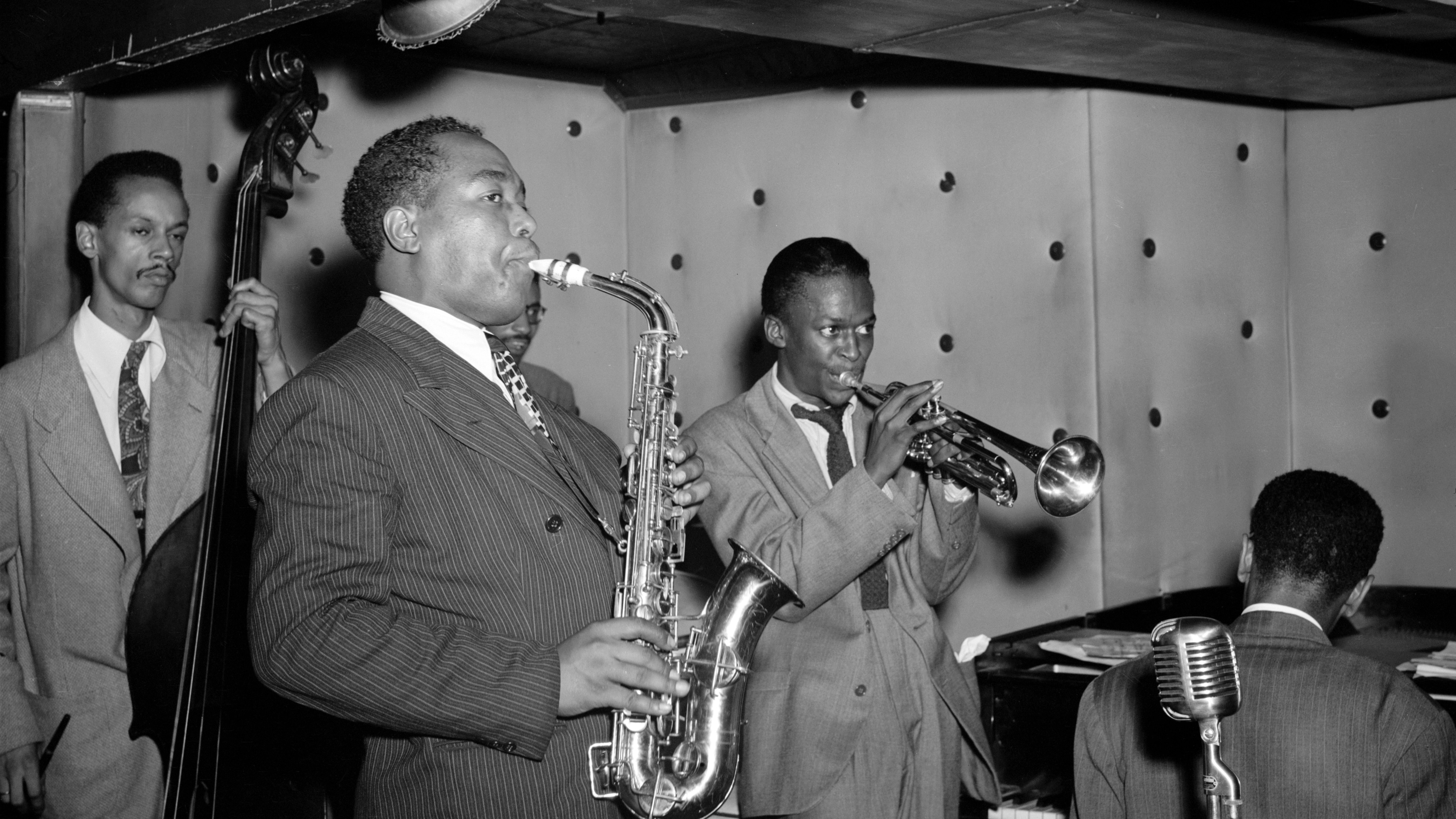 A bop ensemble performing on-stage featuring Charlie Parker on sax and Miles Davis on trumpet