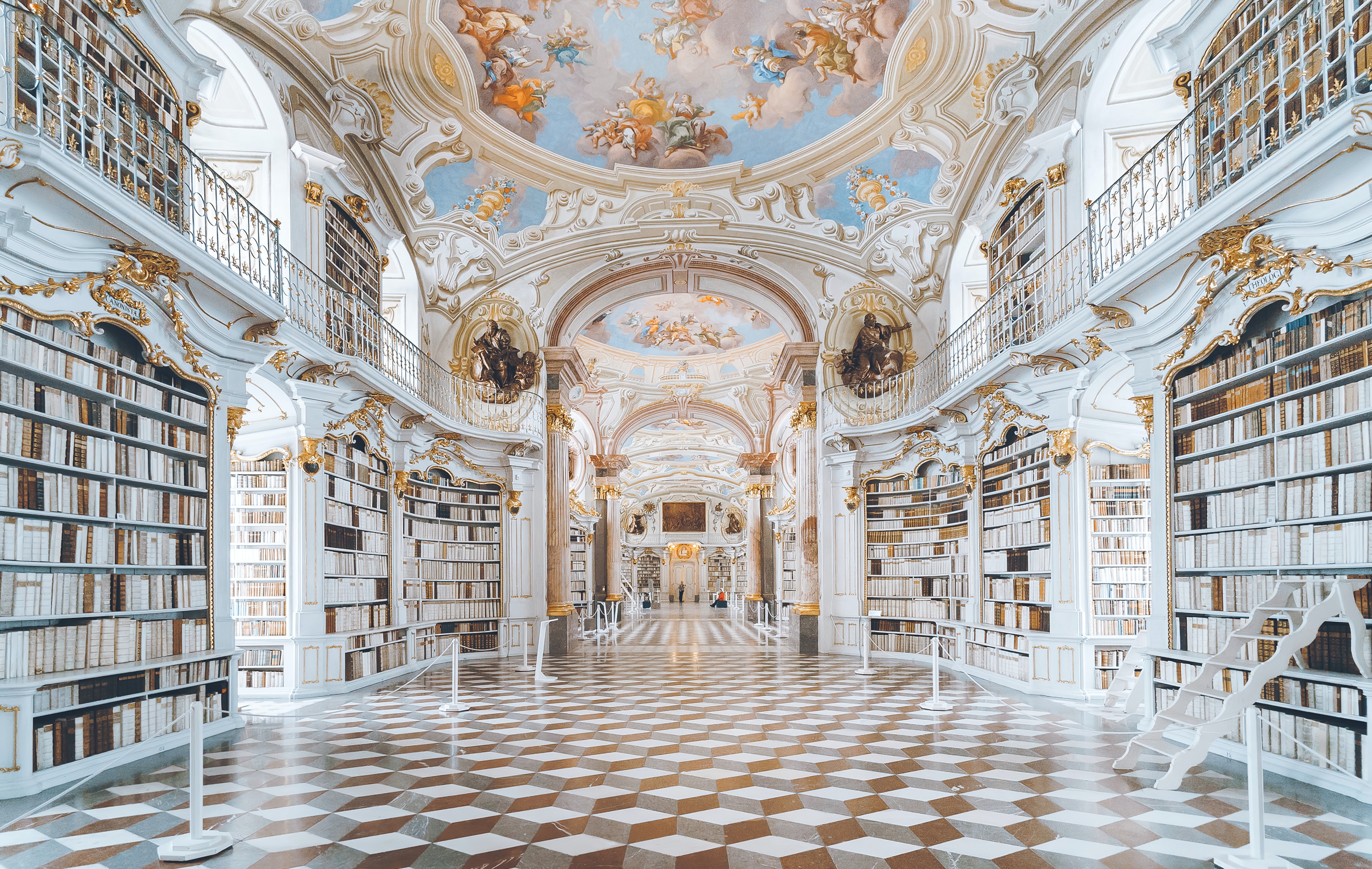 A grand monastery library with white and gold features.