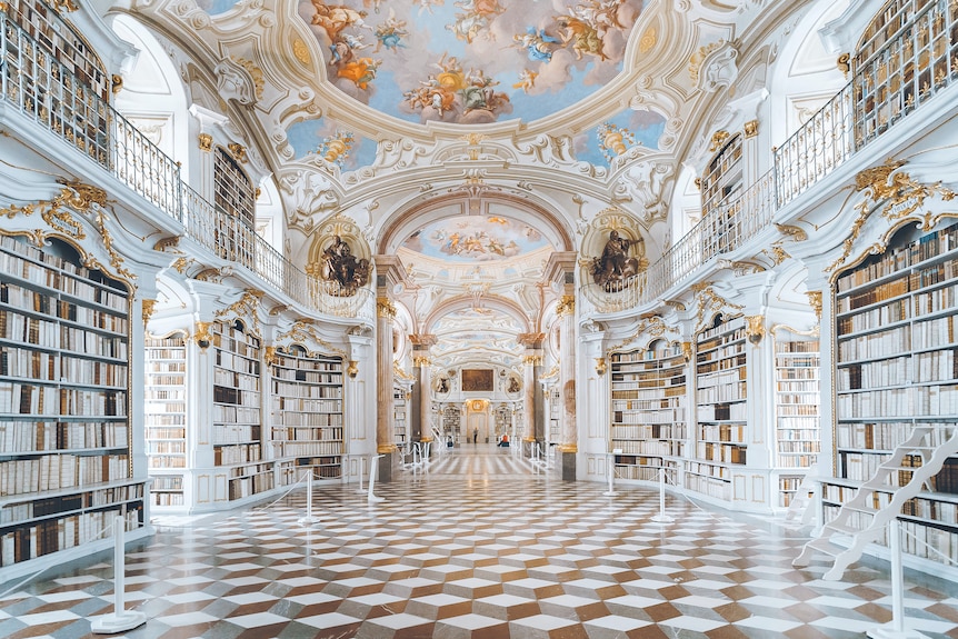 A large monastery library with white and gold elements.