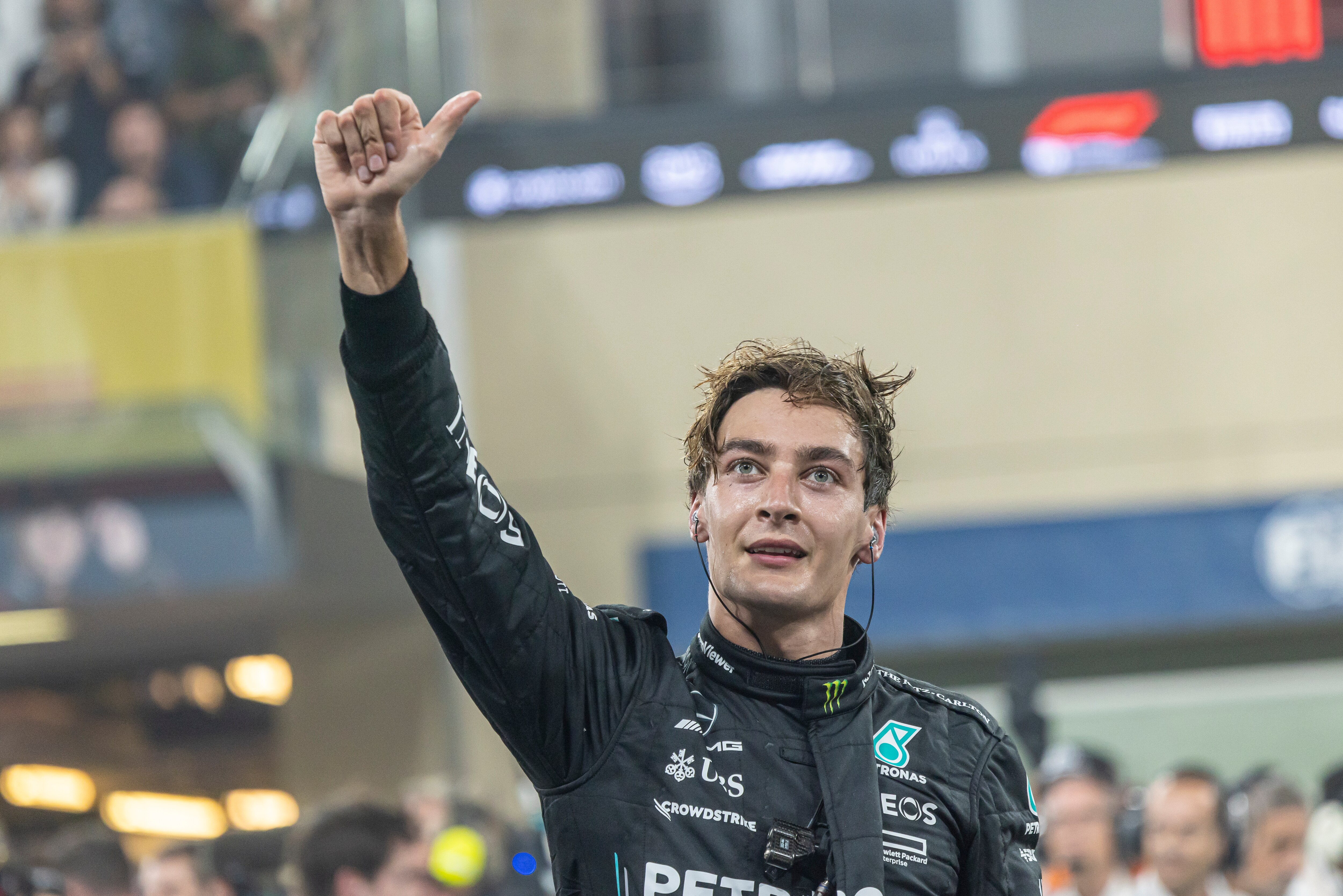 An exhausted F1 drive sticks his thumb-up in celebration, out of the car, sweating
