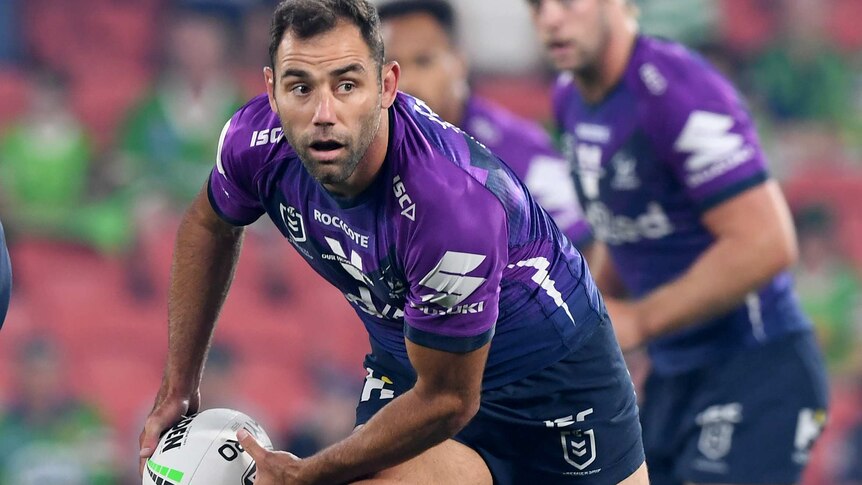 Cameron Smith prepares to pass a rugby ball, wearing a purple kit