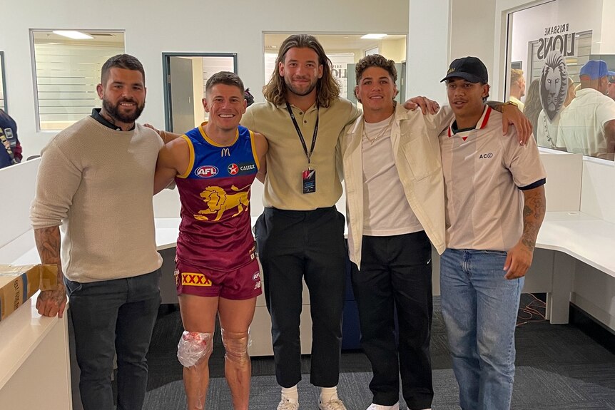 Lions and Broncos members stand together and smile at the camera