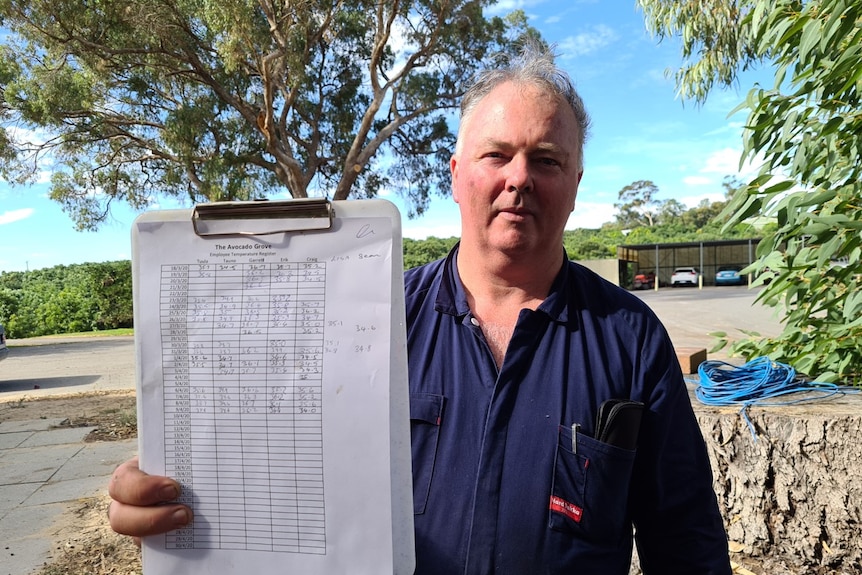 A man stands with a clipboard containing temperature recordings