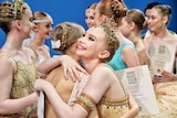 Ballerina hugging another ballerina holding a certificate