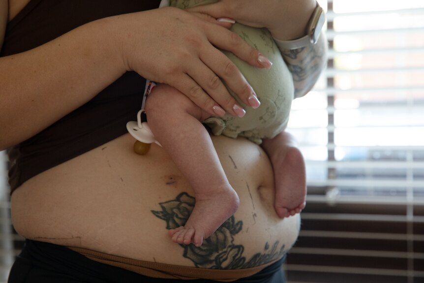 A woman's belly and baby's legs