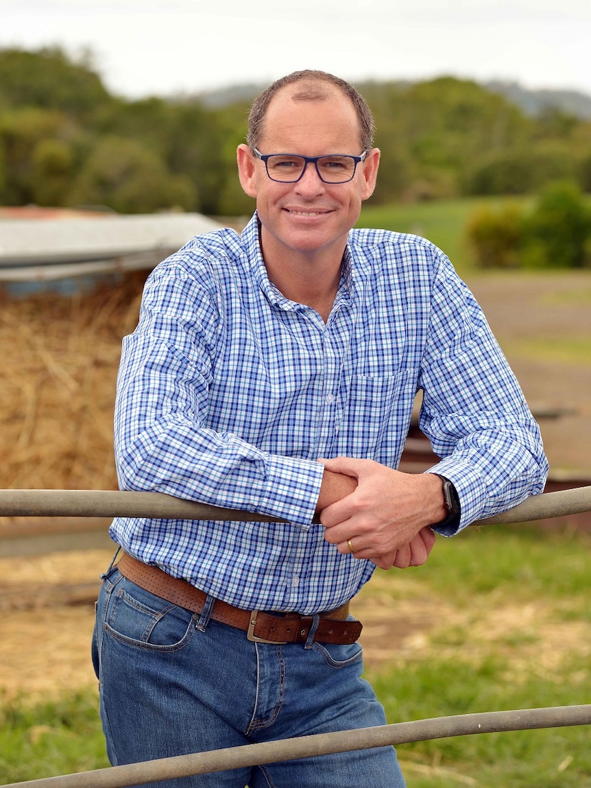 Michael Hampson in a blue and white check shirt leaning over fence.