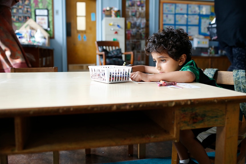 Colour still of Parker Sevak sitting at desk and drawing in classroom in 2018 film The Kindergarten Teacher.