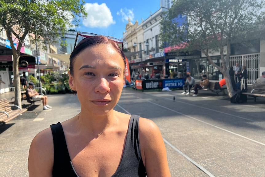 A woman in a black singlet stares at the camera near Bondi Westfield.