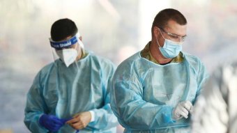 Two men kit up in protective gear to do coronavirus testing