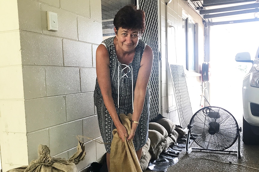 Deeragun resident Robyn Brown holds onto a sandbag as she cleans up her home.