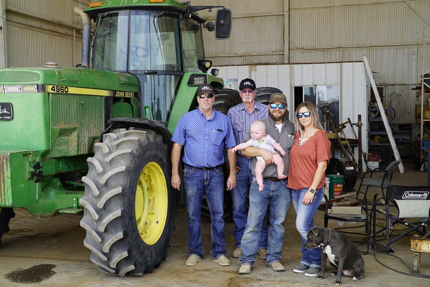 Men and a woman stand near a tractor.