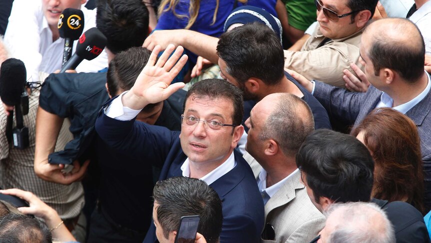 Ekrem Imamoglu waves and looks up from a crowd of people.